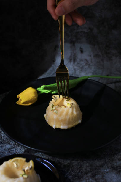 istock Lemon cake with sugar icing under sunlight near yellow tulip on dark background. Cake with citrus traditional American cuisine. 1341964521