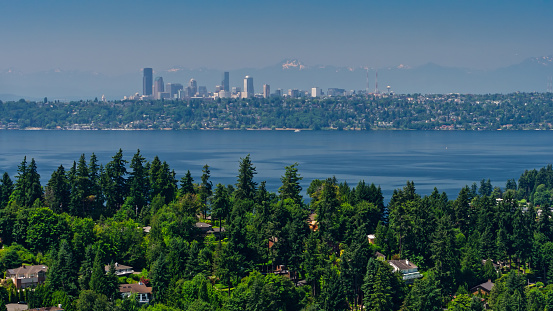 Aerial shot of Bellevue, Washington on a sunny day in summer, looking out over Meydenbauer Bay and Lake Washington towards Seattle, with the snowcapped peaks of the Olympic Mountains in the far distance.