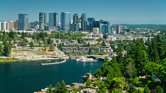 Aerial shot of Bellevue, Washington on a sunny day in summer, looking towards the modern office towers of the downtown from over Meydenbauer Bay past large lakefront houses.