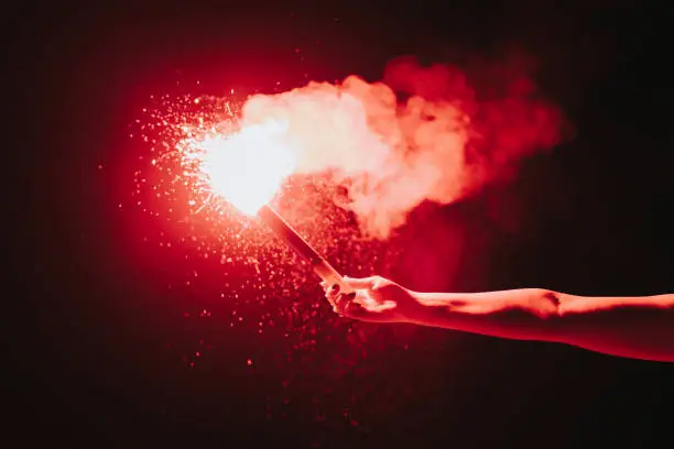 Man holding burning and sparkling Emergency Torch - Flaming Torch with outstreched arm. Emergency Sign Concept Detail.