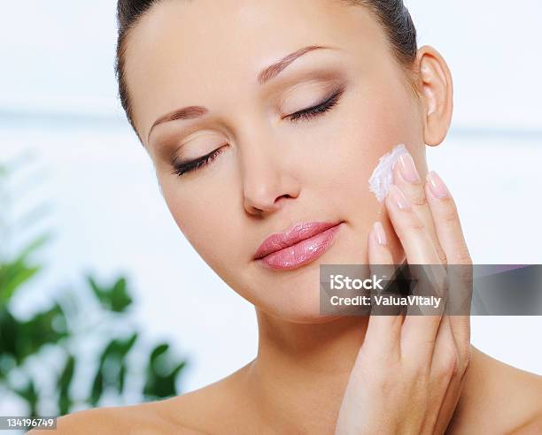 Woman Applying Moisturizer Cream On Her Cheek Stock Photo - Download Image Now - 20-29 Years, Adult, Adults Only