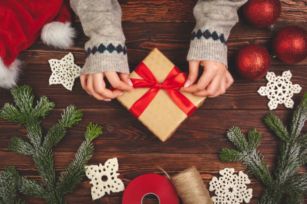 istock Woman holding wrapped Christmas present in her hands, view from above 1341971032