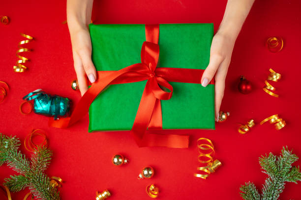 istock Female hands holding present on a red background 1341973490