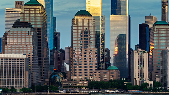 Aerial shot of Lower Manhattan at sunset from over the Hudson River, looking towards Battery Park City with the skyscrapers of the Financial District rising behind.