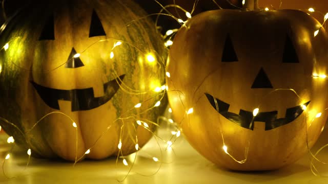 Halloween pumpkin decoration, candles and glowing lights closeup in dark night. Holiday background, festive backdrop