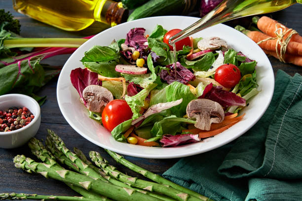 conceitos dietéticos. derramando azeite na salada de primavera tiro de cima na mesa de madeira rústica - alcalino - fotografias e filmes do acervo