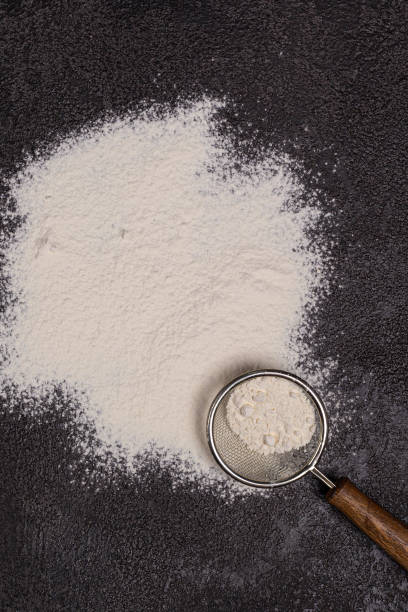 istock Wheat flour in a fine sieve on a black structural background with free space for copying 1341977846