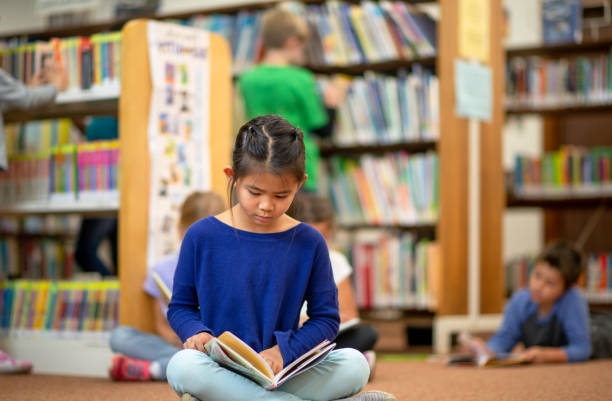 istock Little Girl Reading alone in the Library 1341978021