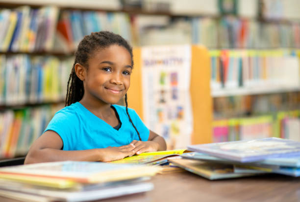 istock Young Elementary Girl Reading a Stack of Books 1341978025