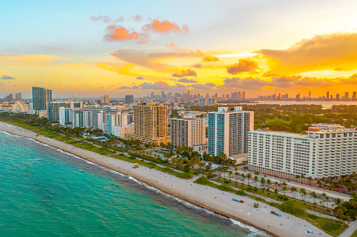 The sun sets with magnificent colors from Miami Beach with the skyline of the city of Miami in frame behind it. Yellow and orange tones on display