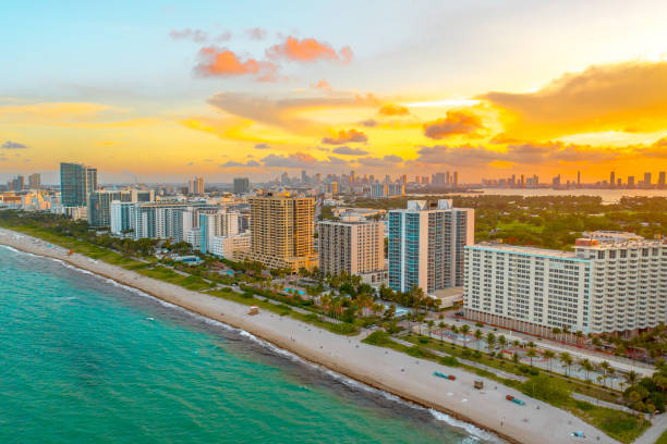 Gorgeous aerial view of sunset in Miami Beach, Florida from a drone The sun sets with magnificent colors from Miami Beach with the skyline of the city of Miami in frame behind it. Yellow and orange tones on display miami photos stock pictures, royalty-free photos & images