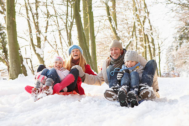 familie sledging durch verschneite wälder - schlittenfahren stock-fotos und bilder