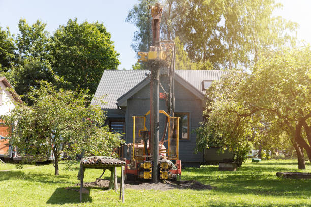 drilling in ground an artesian well for groundwater. mud shooting out of tube. clean water supply. - putten stockfoto's en -beelden