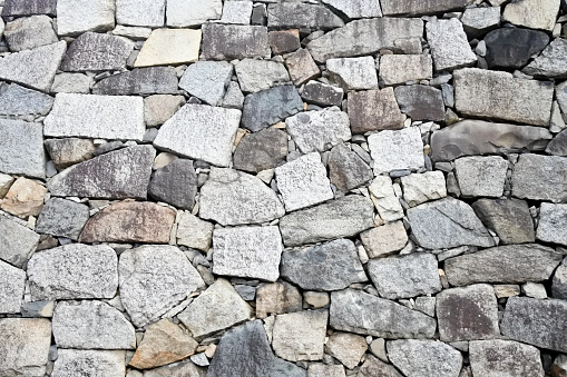 Close-up of ancient red granite stone brick wall, blue clean sky, green grass