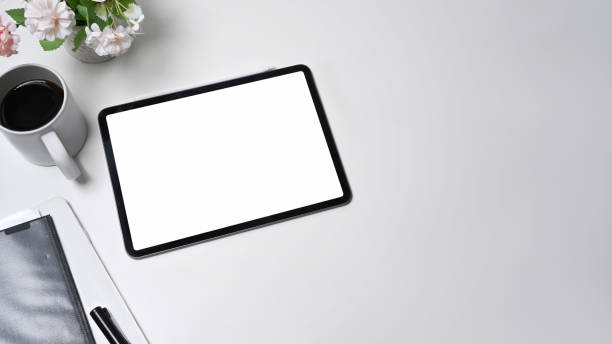 istock Mock up digital tablet, coffee cup and paperwork on white office desk. 1341996486
