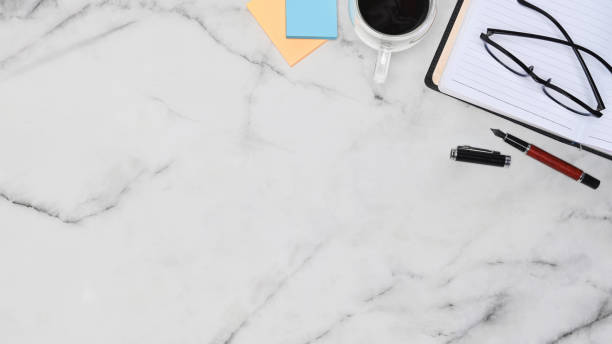istock Stylish workspace with notebook, sticky notes, glasses and coffee cup on marble table. 1341996508
