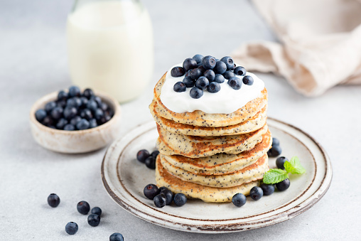Stack of lemon poppy seed pancakes topped with yogurt and blueberries. Healthy breakfast food, low sugar pancakes
