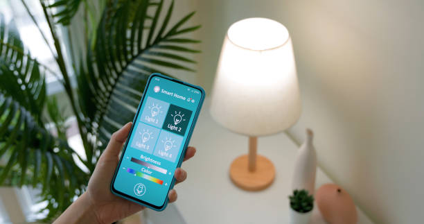 smart home concept smart home concept - asian woman using app to turn on lamp by mobile phone at home internet of things stock pictures, royalty-free photos & images
