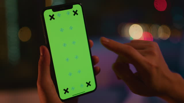 Woman using phone green screen at night