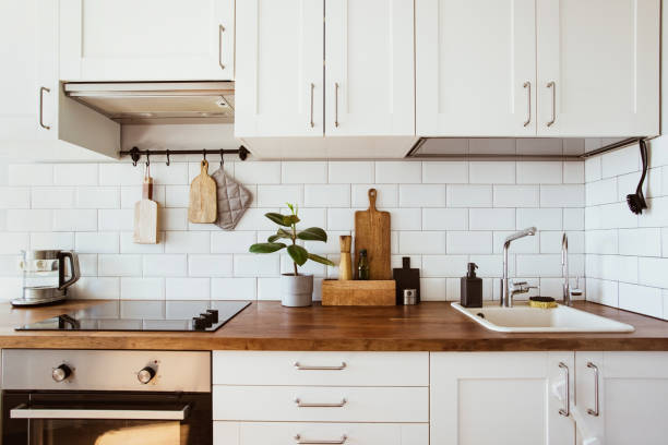 istock Kitchen brass utensils, chef accessories. Hanging kitchen with white tiles wall and wood tabletop.Green plant on kitchen background 1342001418