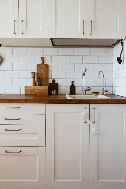istock Kitchen brass utensils, chef accessories. Hanging kitchen with white tiles wall and wood tabletop.Kitchen background 1342001479
