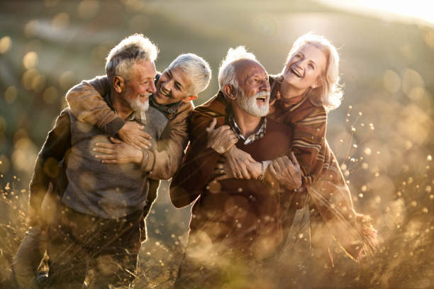 istock Happy mature couples having fun while piggybacking in autumn day. 1342002308