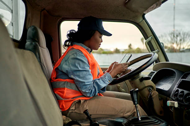 スマートフォンをチェックする20代半ばのブラックトラック運転手 - independence business women manual worker ストックフォトと画像