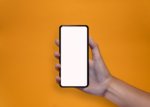Hands holding a smartphone on yellow background