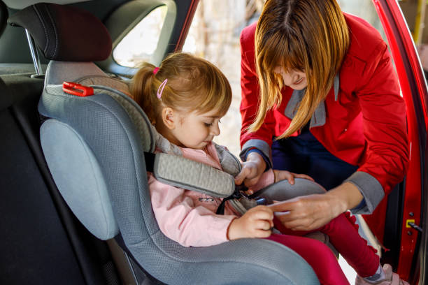 istock Mother securing her daughter in car seat 1342006571