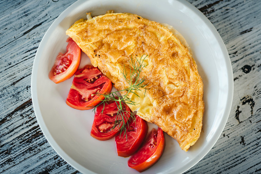 Omelette with cheese and fresh tomatoes garnish.