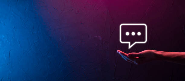 istock Hand on neon background holding a message icon, bubble talk notification sign in his hands. Chat icon, sms icon, comments icon, speech bubbles 1342012933