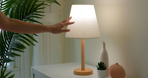 woman is turning on lamp by touching with induction light at home