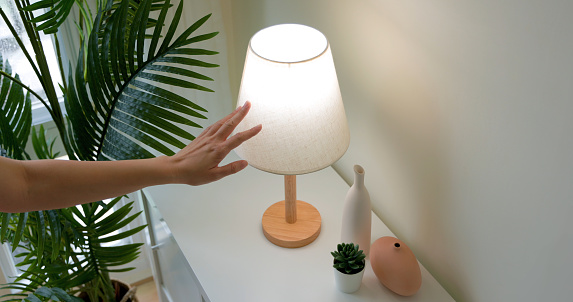 woman is turning on lamp by touching with sense light at home