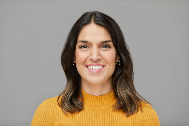 istock A happy young woman's headshot in a yellow sweater. 1342013370