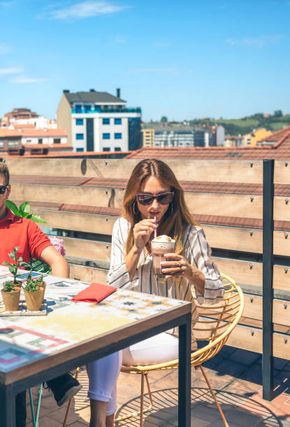 istock Woman with sunglasses having a milkshake on a terrace 1342014816