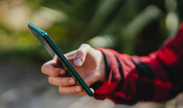 istock Close up of woman hand using smartphone, outdoors in park. Copy space. 1342017175