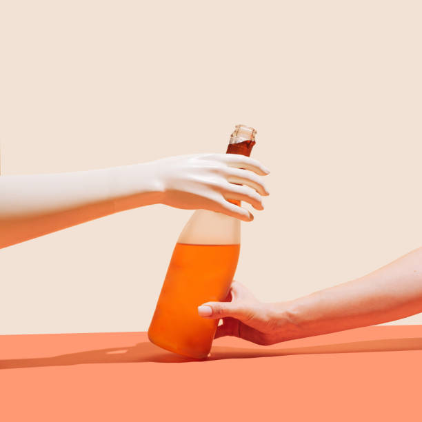 istock Knowledge sharing and cultural diversity concept. Artificial hand receiving bottle of champagne from girls hand. Beige and terracotta background 1342017315