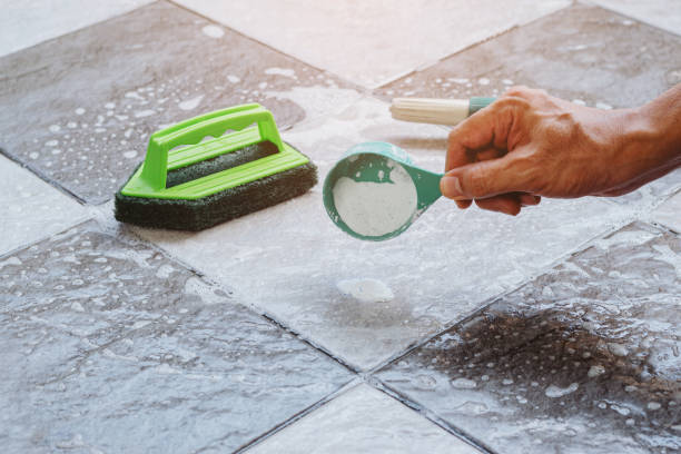 Human hand pouring the detergent on the wet tile floor to clean it. stock photo