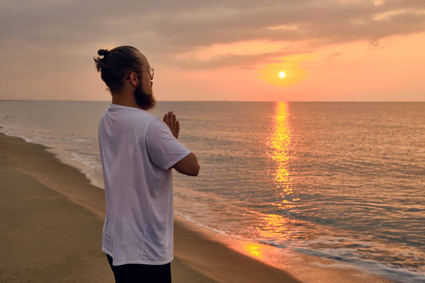 istock Man practices Surya Namaskar pose at sea beach 1342020364