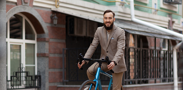 An entrepreneur is on his way to work. A bearded man riding a bicycle. Promoting exhaust emission reduction.