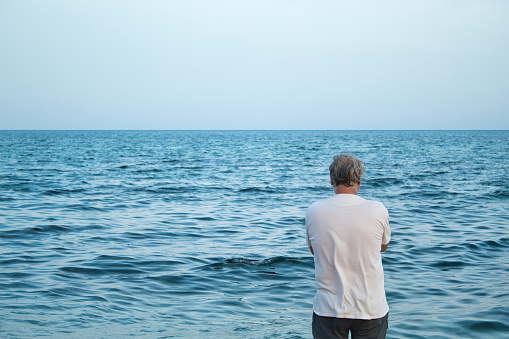 view from behind of mature man with grey hair enjoying on seashore