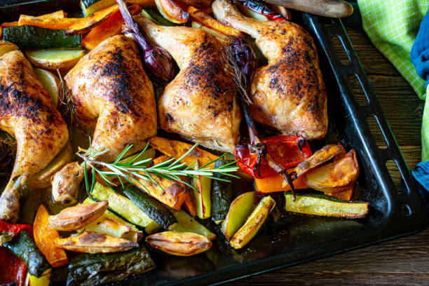 Healthy family meal with chicken and vegetables Homemade fresh cooked healthy family meal with roasted chicken legs and oven baked vegetables served on a baking tray on wooden table. Closeup view mediterranean food stock pictures, royalty-free photos & images