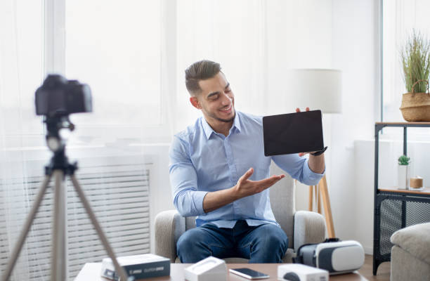 istock Arab male vlogger making video review of innovative tablet pc, using camera at home, mockup on touch pad screen 1342027472