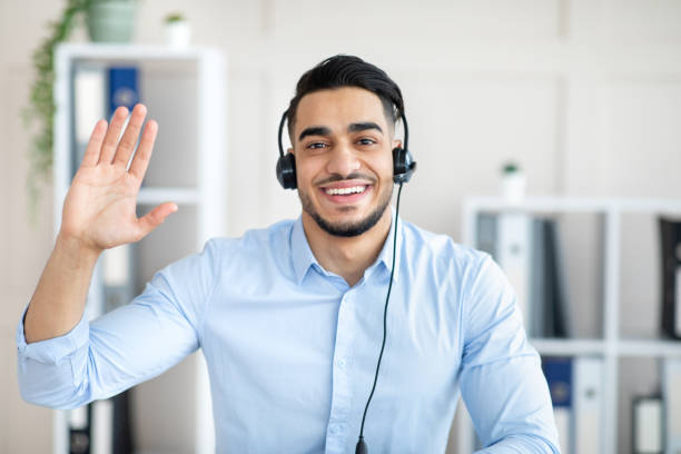 istock Remote communication concept. Happy Arab guy with headset having video call at office, waving at webcam 1342027481