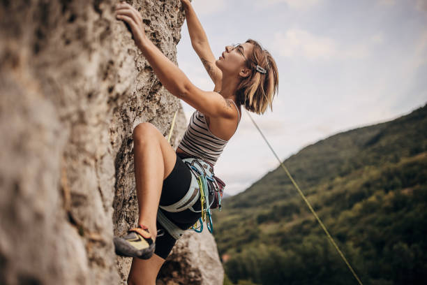 junge frau klettert auf der klippe - climbing stock-fotos und bilder