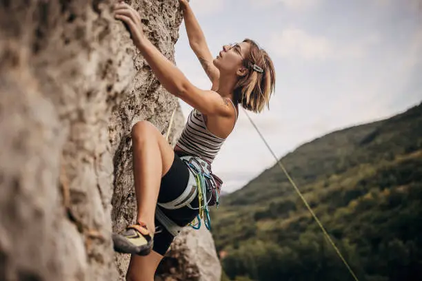 Photo of Young woman rock climbing on the cliff