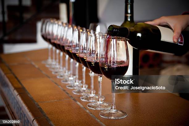 Mano Vertiendo Una Hilera De Copas De Vino Para Probar Foto de stock y más banco de imágenes de Vino