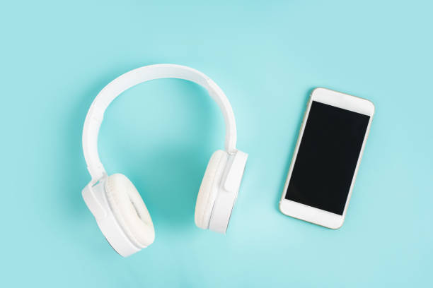 istock Mobile phone with blank screen and white headphones on a blue table top view 1342028986
