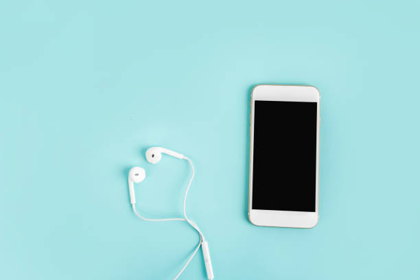 istock White headphones and mobile phone with blank screen on a blue table top view. 1342028987