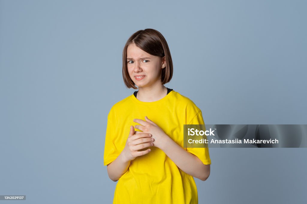 teen girl has disgusting expression as sees something unpleasant, stand over light grey background. Ugh how disgusting teen girl dressed in yellow casual t shirt has disgusting expression as sees something unpleasant, stand over light grey background. Ugh how disgusting Scented Stock Photo